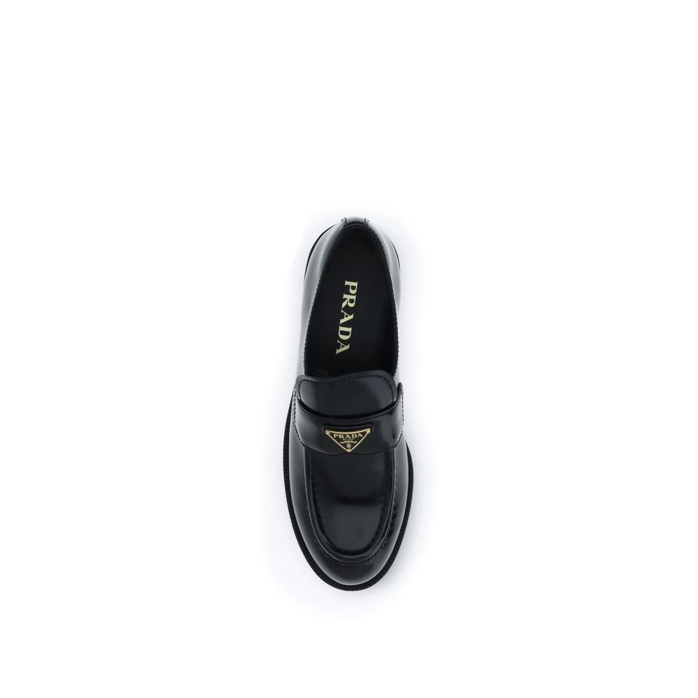 Prada Loafers Neri in Pelle Lucida Logo Triangolo Metallico SS26